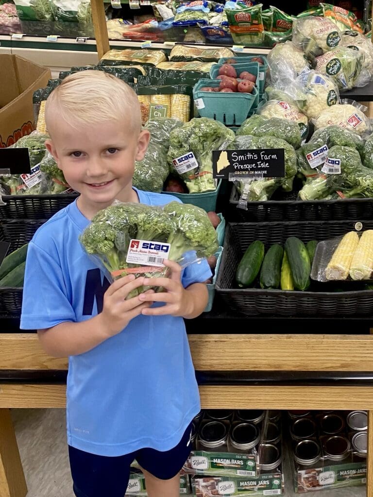 A young boy providing a testimonial in front of a display of vegetables.